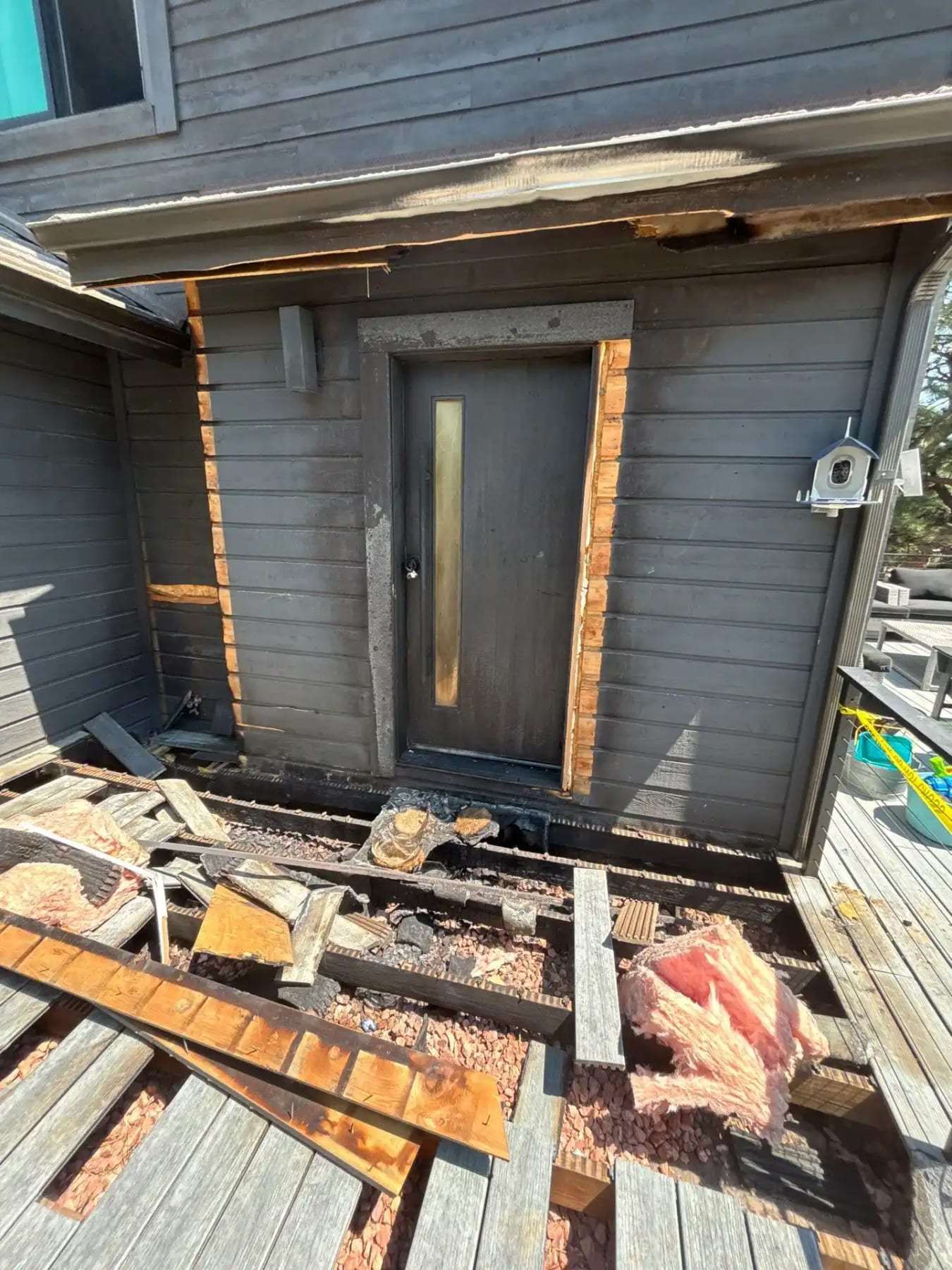 Deck boards removed at an exterior door to expose rotted framing