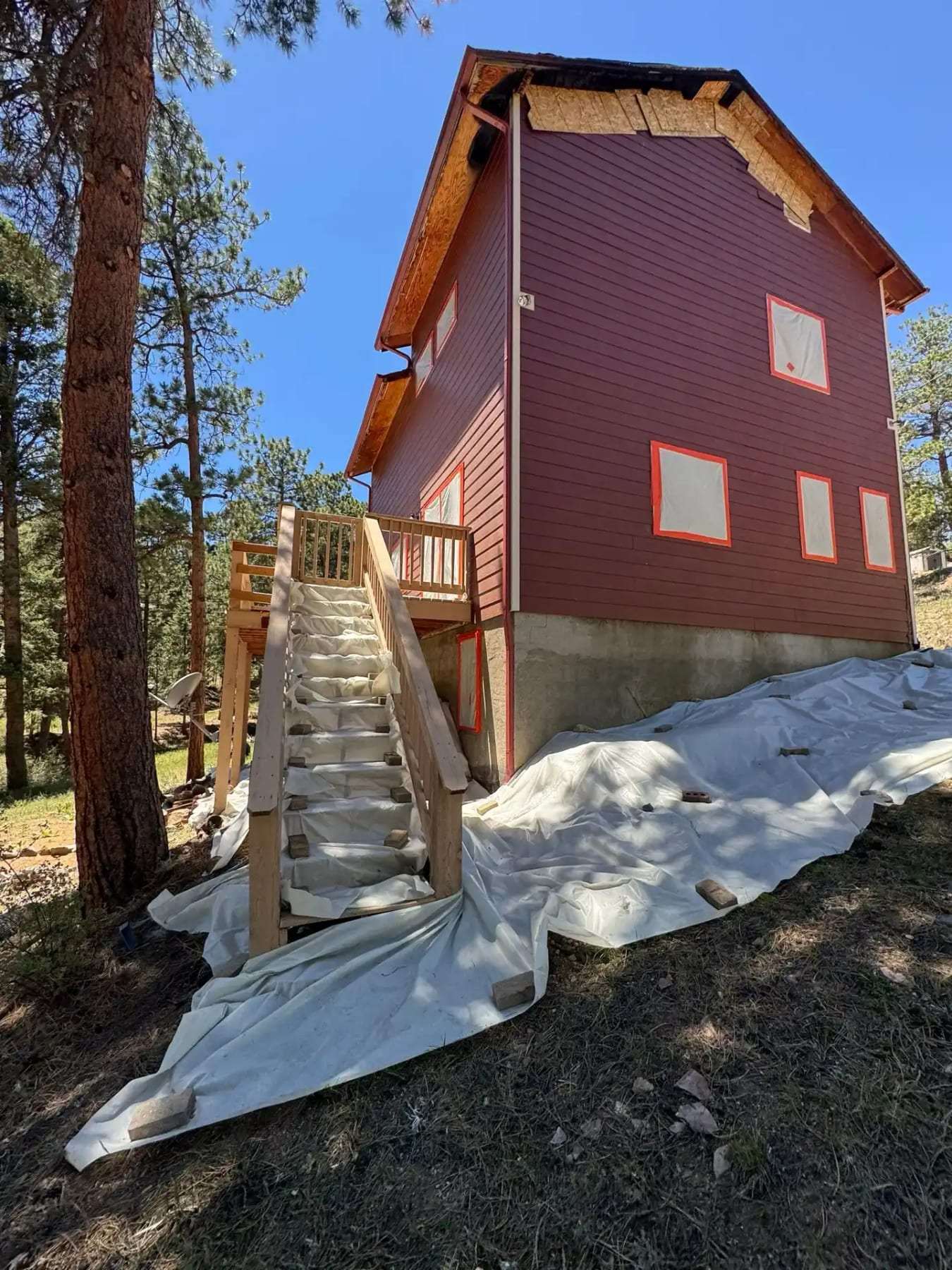 Mountain home exterior with a new stair and plastic sheeting on the ground