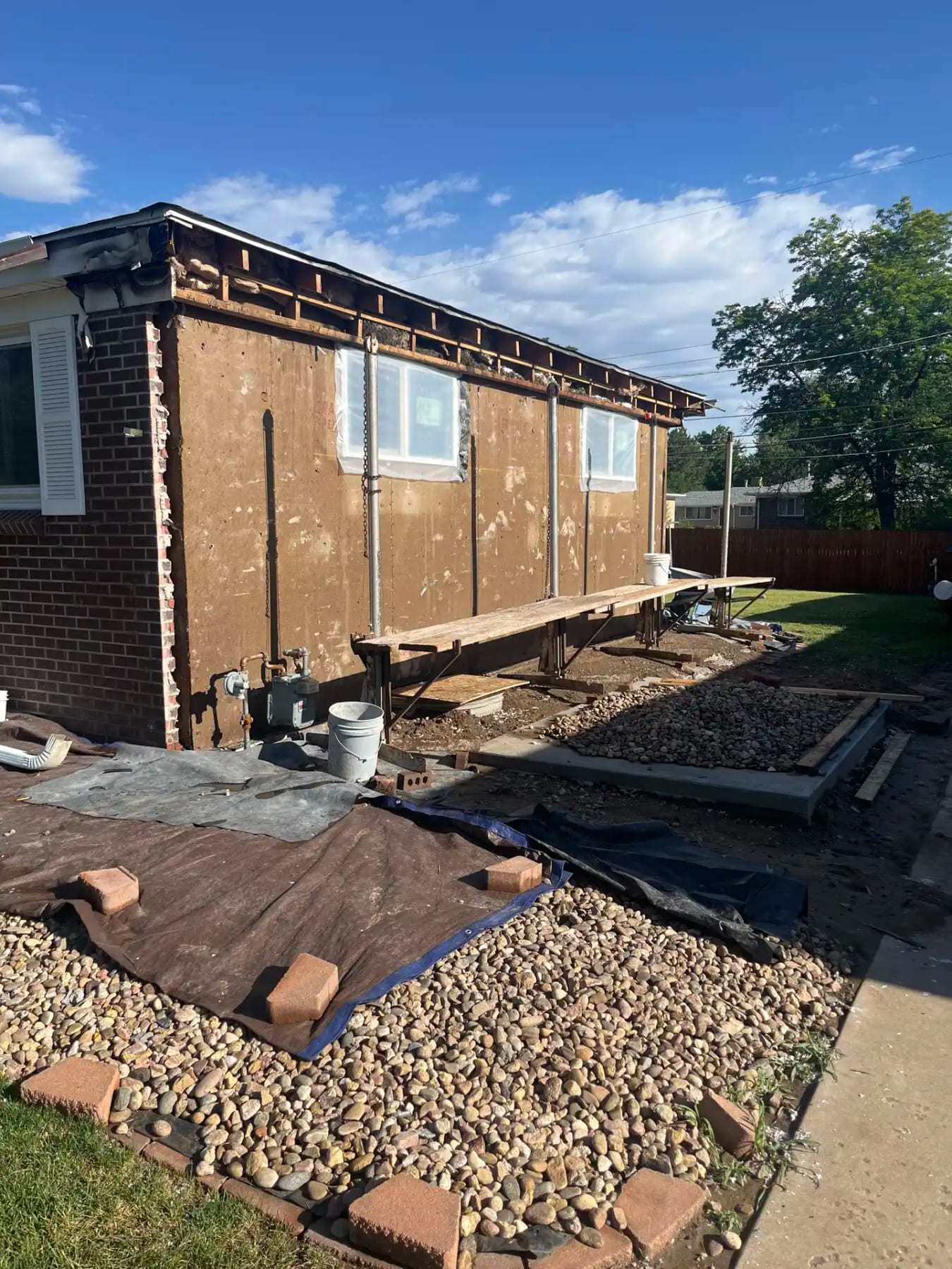 House exterior with stucco removed and pavers lifted along the foundation