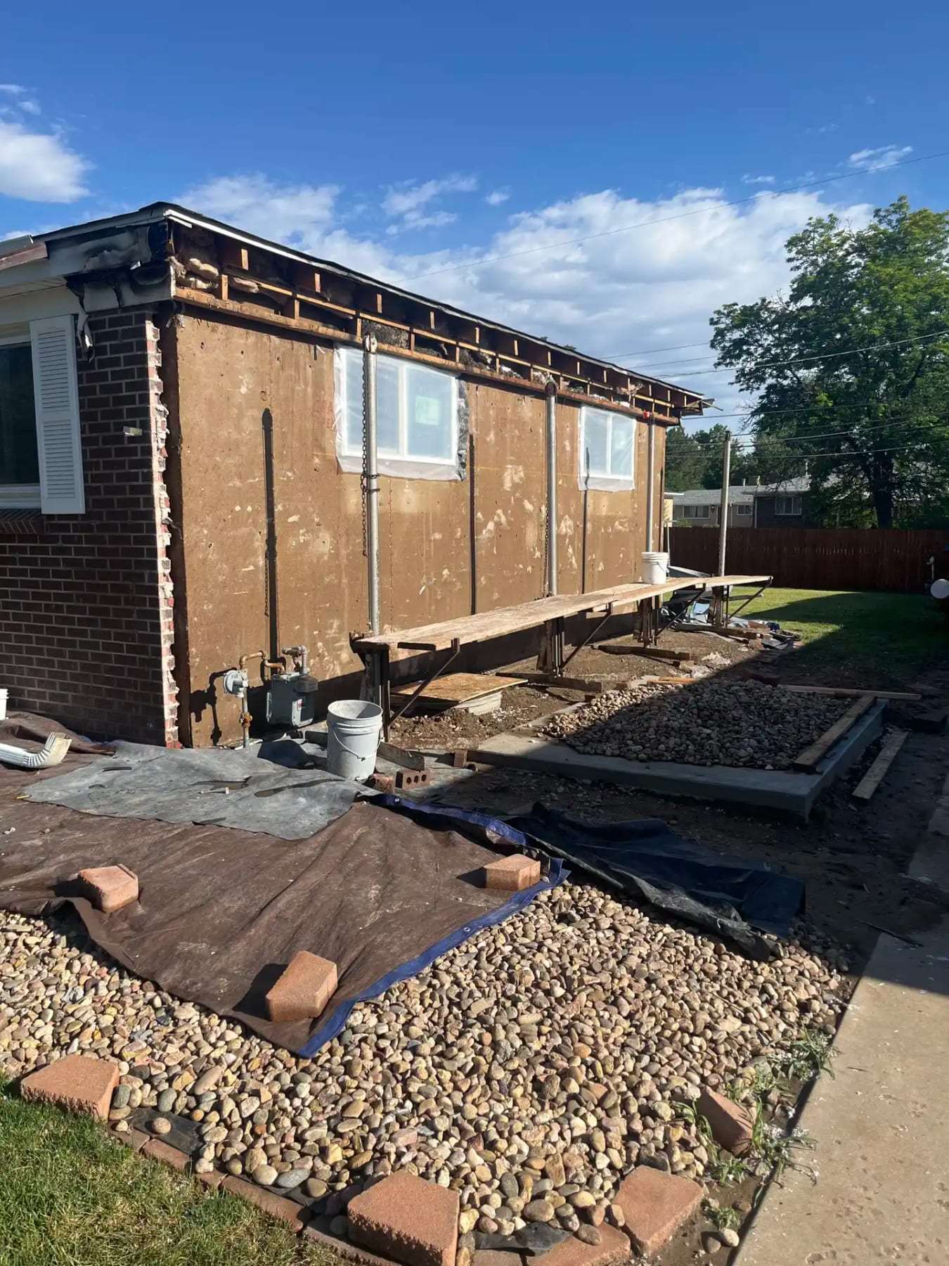 House exterior with stucco removed and pavers lifted along the foundation
